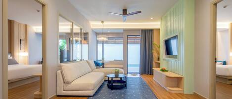 A modern hotel room with a sofa, a small table, a TV, and a balcony with a view.