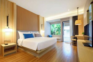 A modern hotel room with a large bed, bedside tables, a desk, and a TV.