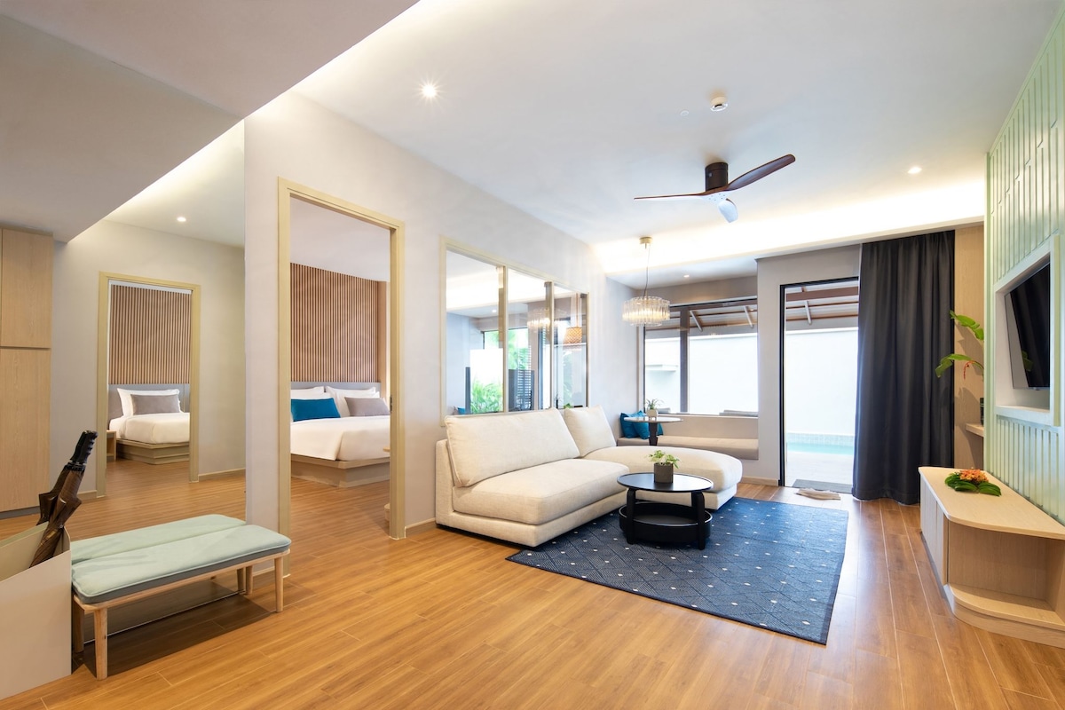Une chambre d’hôtel moderne équipée d’un canapé, d’une petite table, d’un banc, d’un ventilateur de plafond et d’une grande fenêtre.