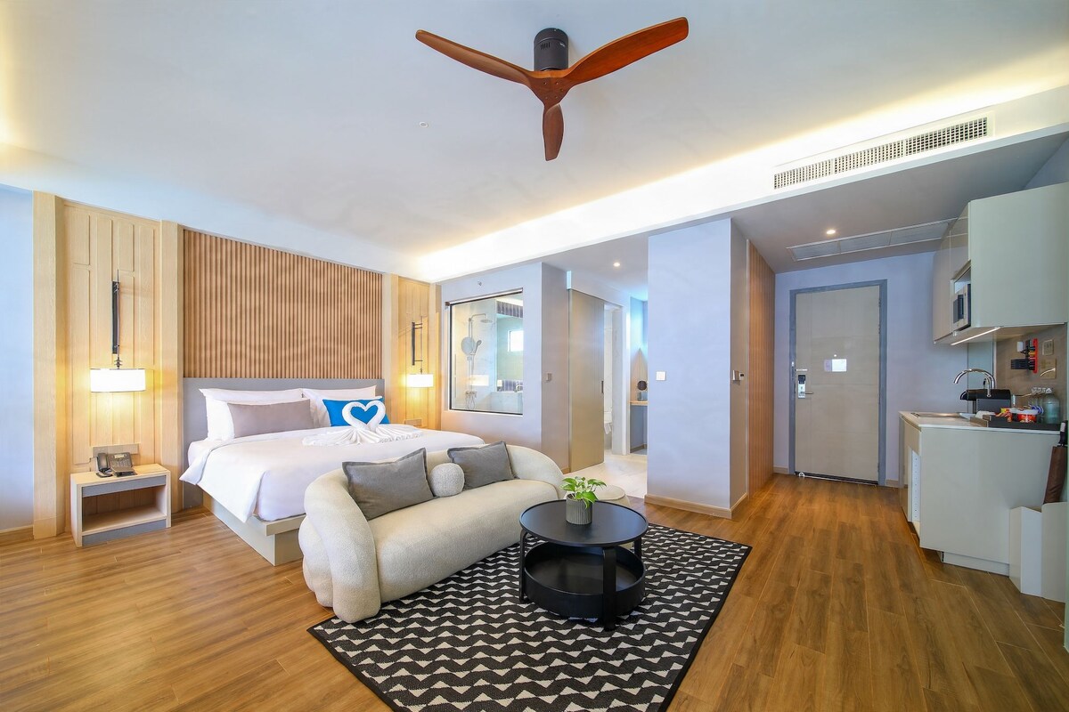 A modern hotel room with a bed, bedside table, lamp, and a ceiling fan.