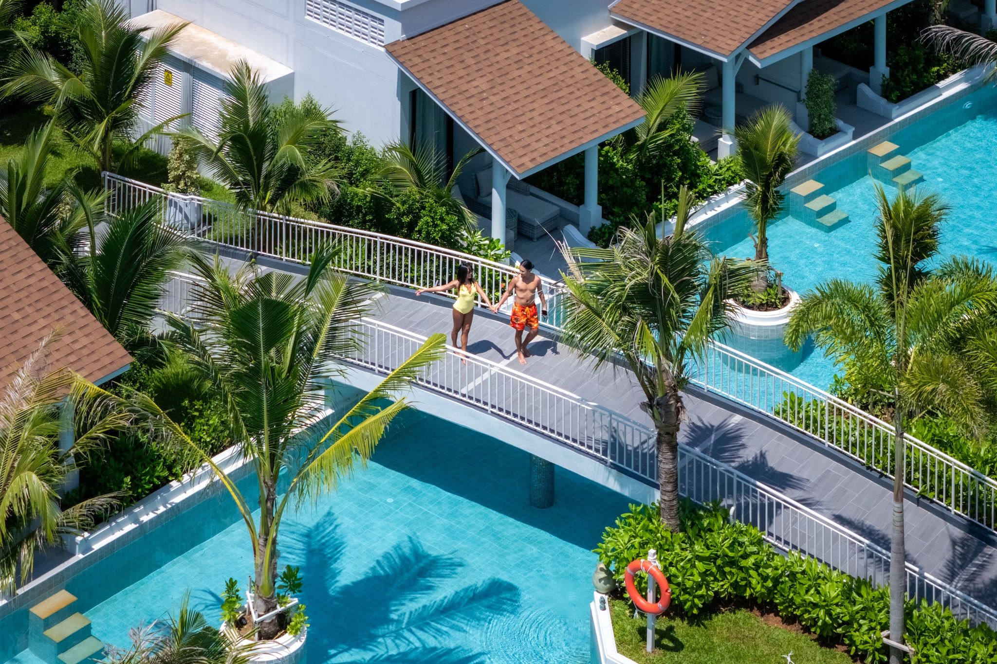 Un complexe hôtelier doté d’une piscine, de palmiers et d’une allée couverte.