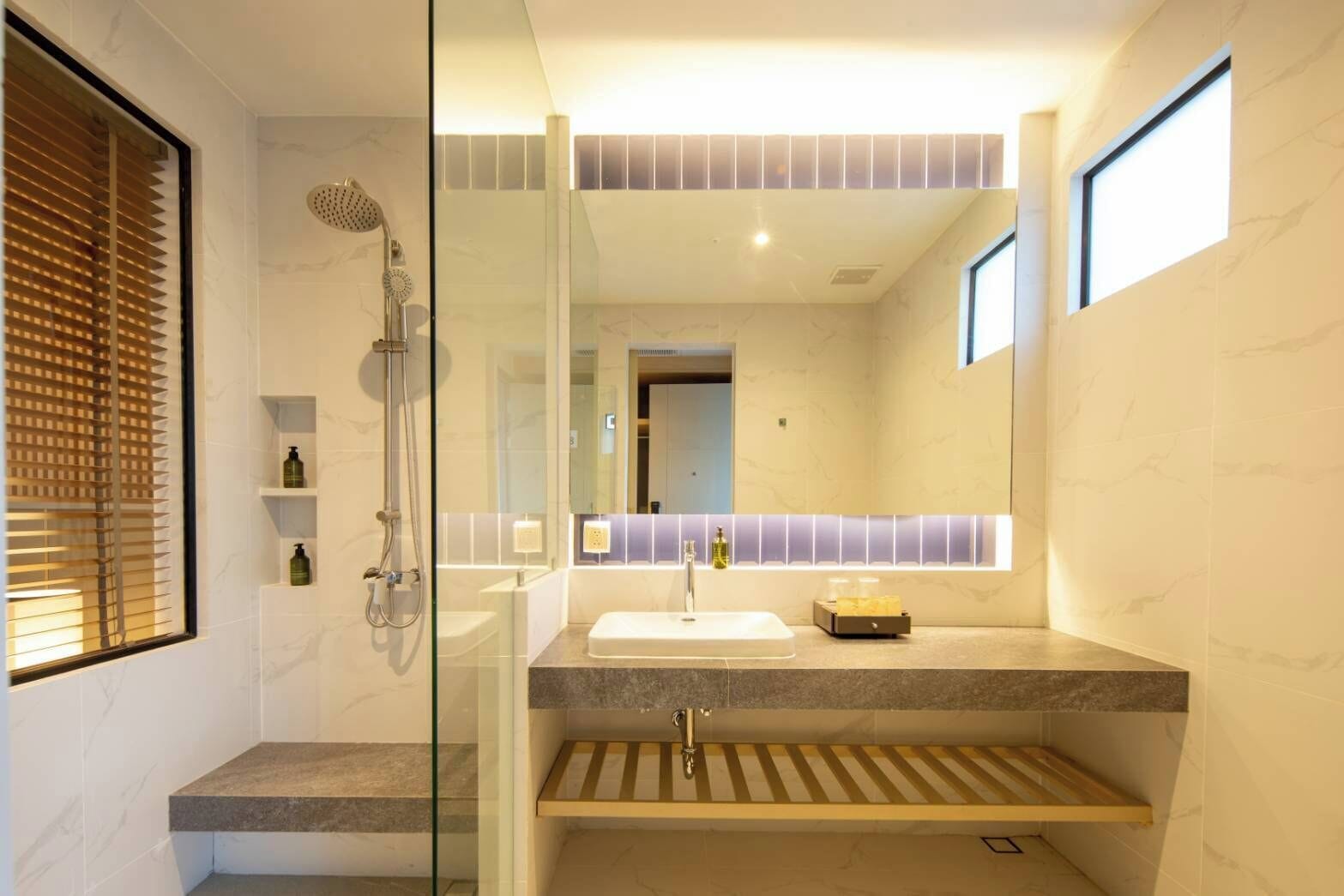 A modern bathroom with a glass shower enclosure, a vanity with a sink, and a mirror.