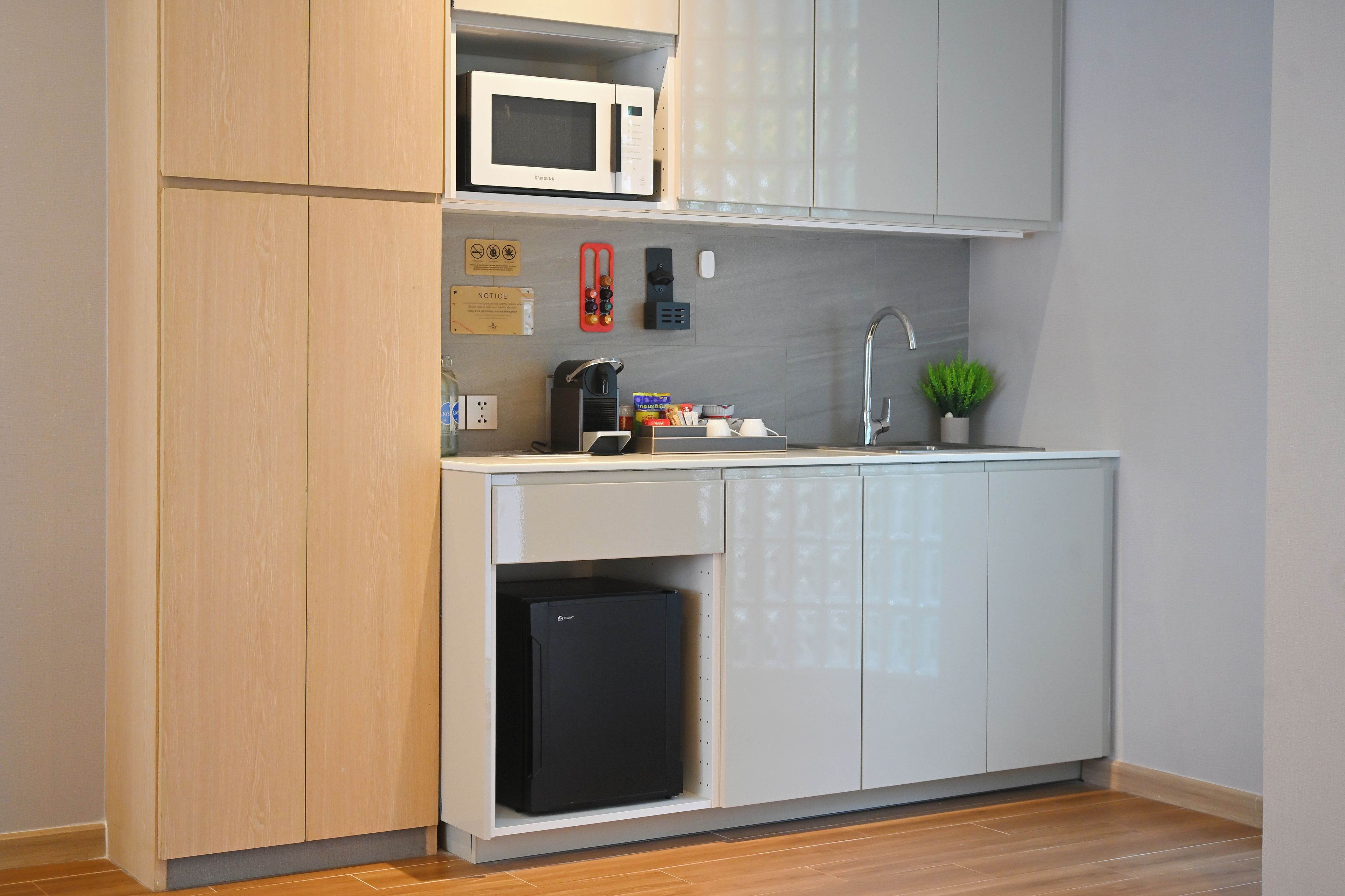 A compact kitchen with a microwave, coffee machine, sink, and a small refrigerator.