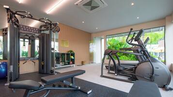 Un gimnasio con equipo de ejercicio, una banca y un ventanal con vistas a zonas verdes.