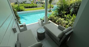 Un balcon avec vue sur une piscine, des sièges confortables et une table en osier.