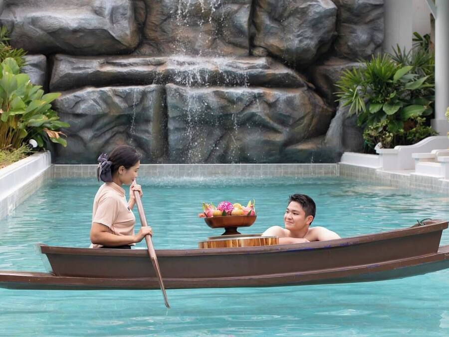 Un bote en una piscina con una cascada de fondo.
