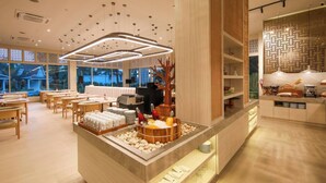 A modern hotel lobby with wooden furniture, a reception desk, and a view of the outdoors. - Lalynn Resort & Villas (Thep Krasattri)
