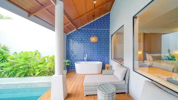 Un baño moderno con una bañera independiente, un espejo grande y vistas a una piscina.