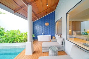Un baño moderno con una bañera independiente, un espejo grande y vistas a una piscina.