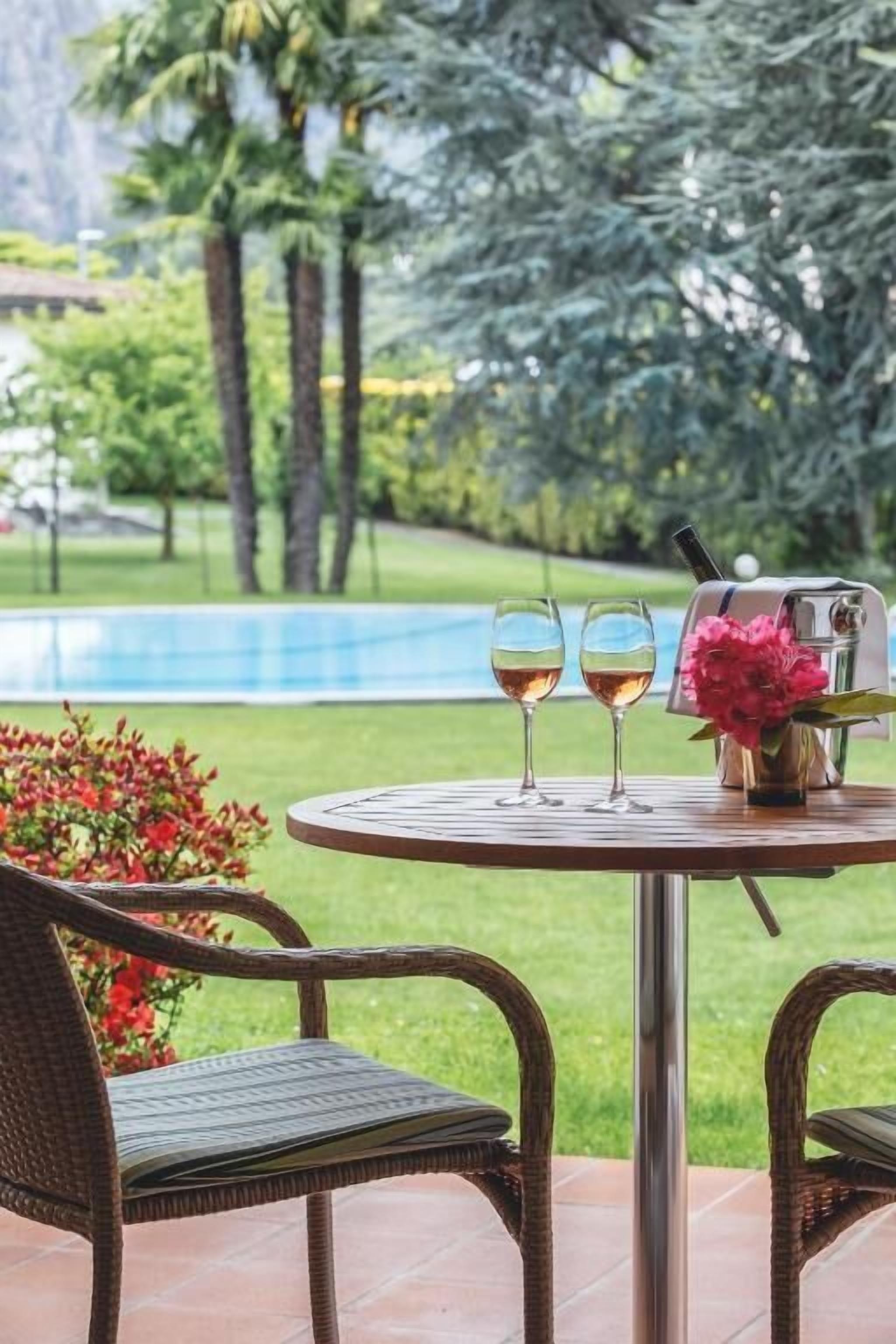A round table with two wine glasses, a flower vase, and a grill.