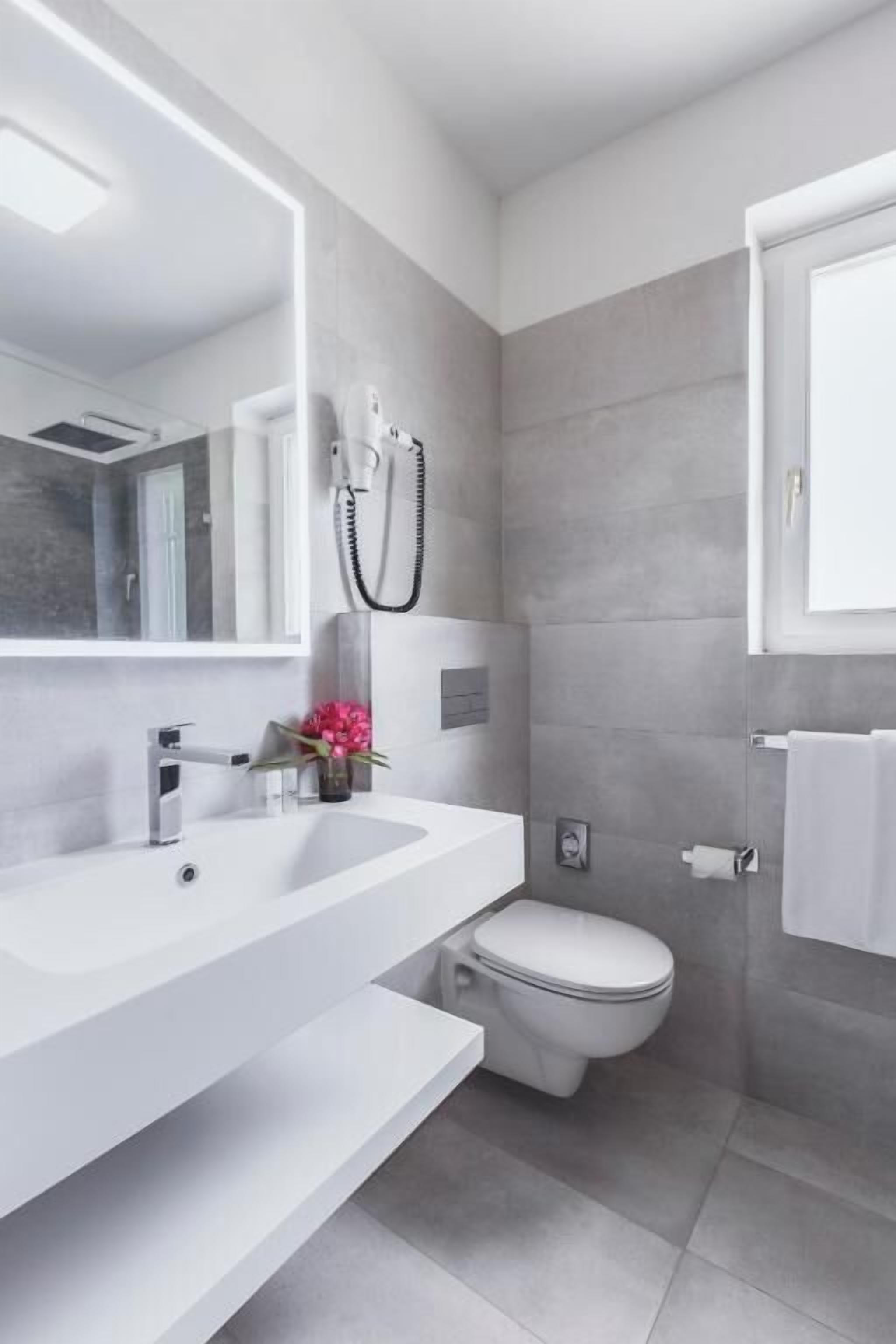 Une salle de bain moderne avec un lavabo blanc, des toilettes et un miroir.