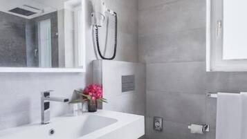 A modern bathroom with a white sink, a toilet, and a mirror.