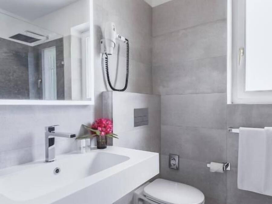 A modern bathroom with a white sink, a toilet, and a mirror.