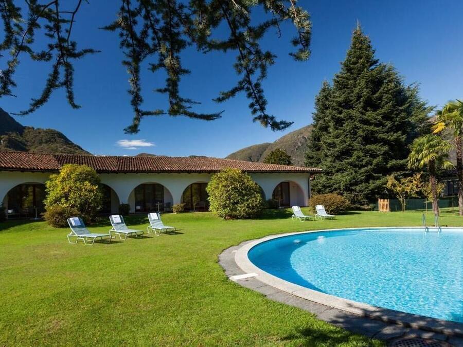 A pool area with a clear blue pool, surrounded by a well-maintained lawn and lounge chairs.