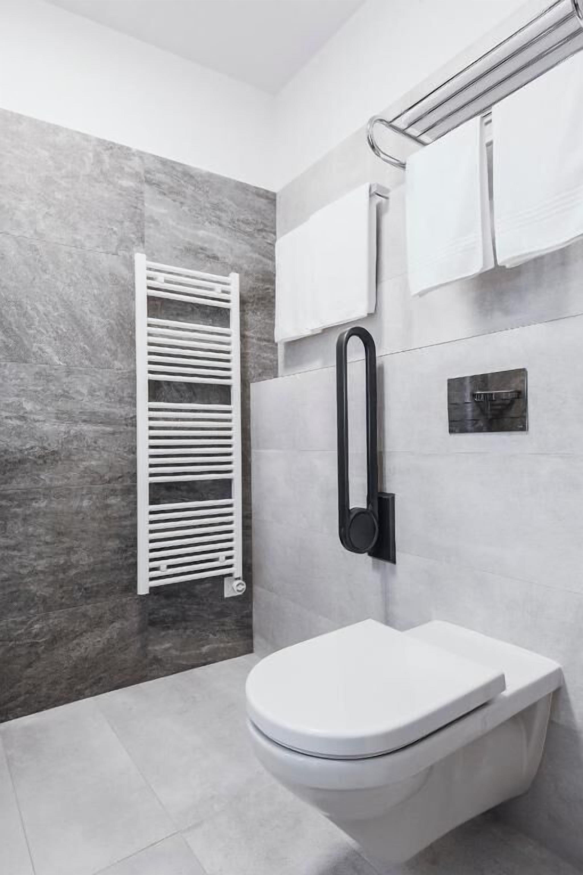 Ein modernes Badezimmer mit Toilette, Handtuchhalter und Handtuchspender.