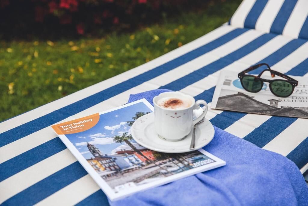 Un fauteuil de détente à rayures, avec un magazine, une tasse de café et des lunettes de soleil.
