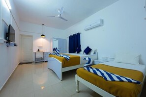 A hotel room with two beds, a desk, a chair, a TV, a ceiling fan, and an air conditioning unit. - MADRAS INN - NUNGAMBAKKAM (Chennai)