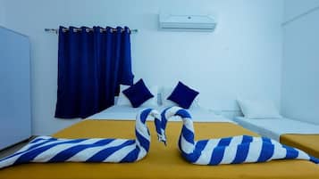 A hotel room with a bed, two pillows, a curtain, and an air conditioning unit.