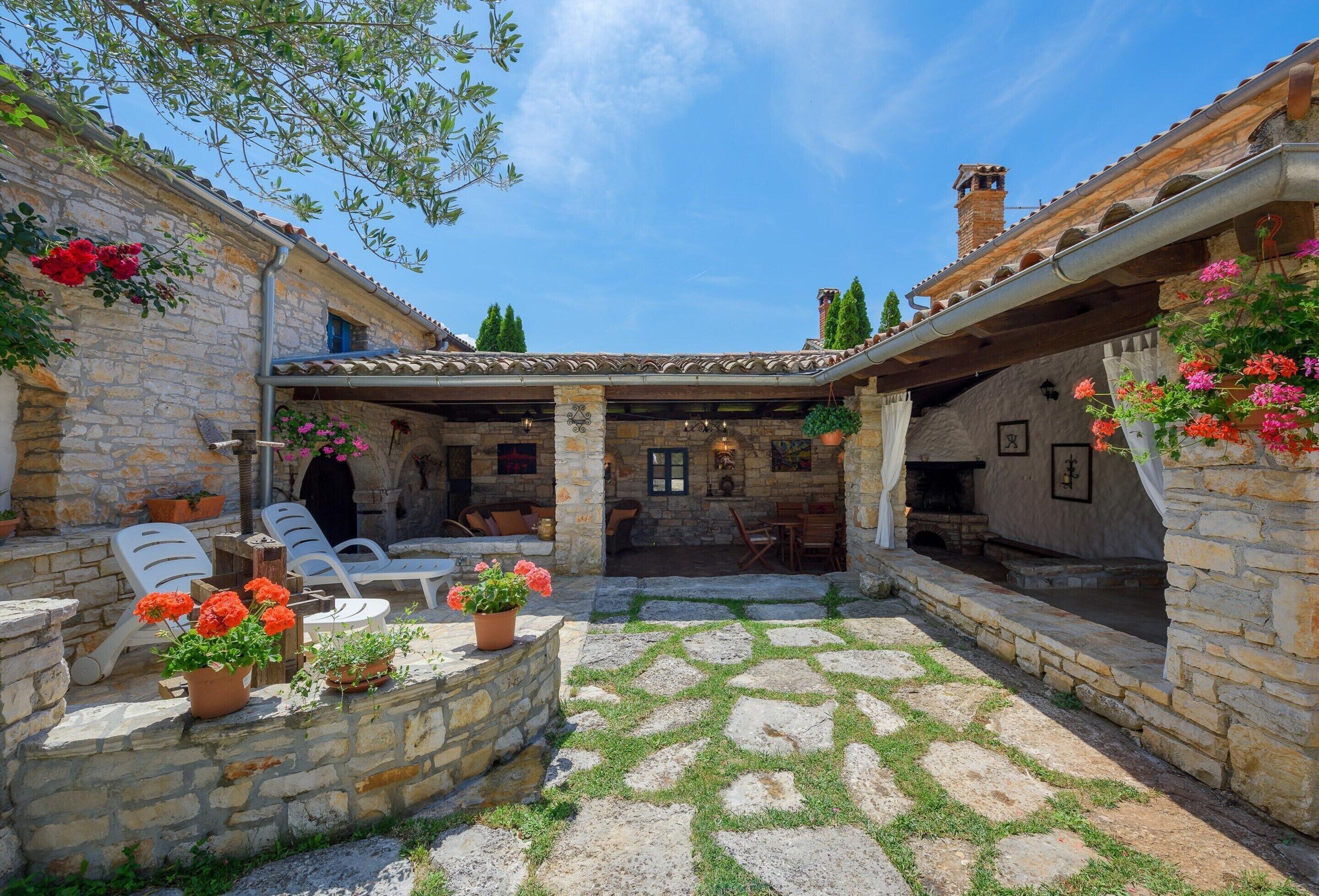 A stone courtyard with outdoor seating, a fireplace, and potted plants.