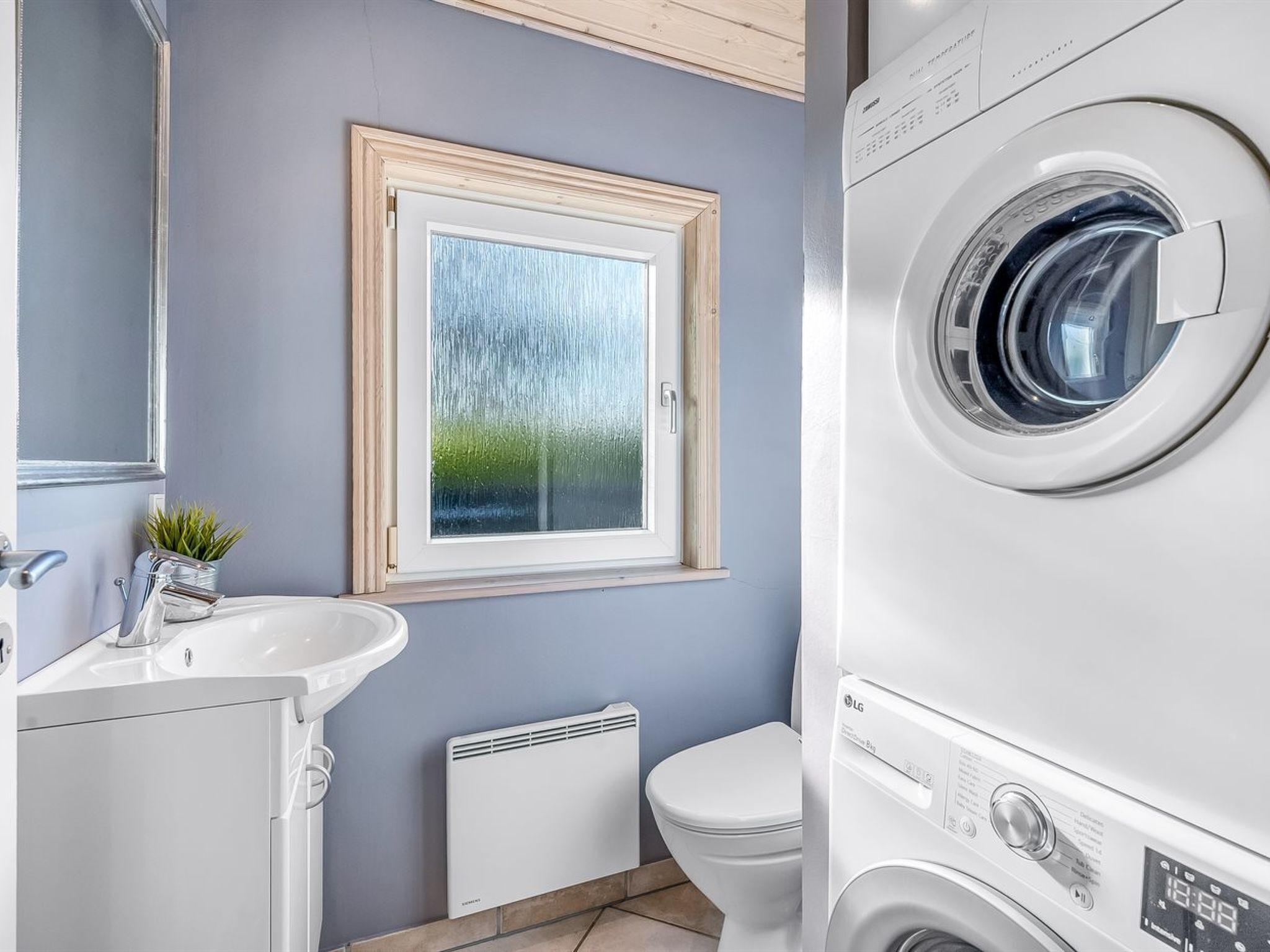 A modern bathroom with a built-in washing machine, a sink, and a toilet.