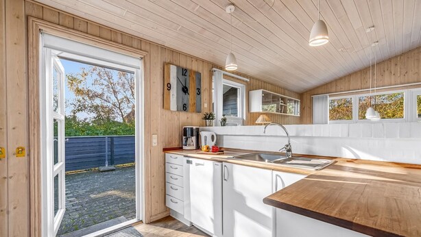 A modern kitchen with wooden cabinetry, a built-in oven, and a large window. - "Efka" - 600m to the fjord by Interhome (Tarm)