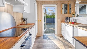 A modern kitchen with wooden cabinets, a stainless steel range hood, and a large island with a built-in oven. - "Efka" - 600m to the fjord by Interhome (Tarm)