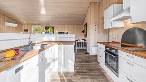 A modern kitchen with wooden cabinets, a central island, and a view to the dining area. - "Efka" - 600m to the fjord by Interhome (Tarm)