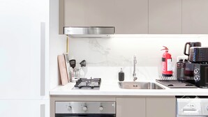 A modern kitchen with a built-in oven, a gas stove, a stainless steel sink, and a coffee maker. - Urban Charm: Studio With Balcony in Riviera (Dubai)