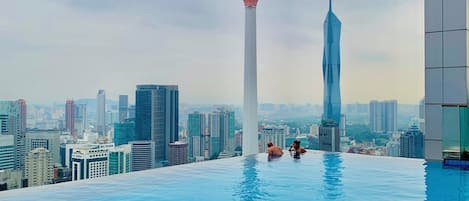 A rooftop infinity pool with a city skyline in the background, including a prominent tower.