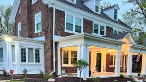 A two-story brick house with a covered front porch, a small tree, and a well-maintained lawn. - Private Garden Unit Gary BP (Gary)