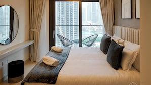 Habitación de hotel moderna con una cama grande, dos sillas, una mesita y vistas a la ciudad.