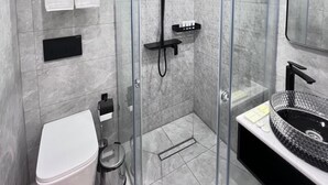 A modern bathroom with a glass-enclosed shower, a white toilet, and a black sink with a circular basin. - K HOTEL RESTURANT (Bishkek)