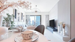 Een moderne hotelkamer met een zithoek, een bank, een televisie en een balkon met uitzicht op de stad.