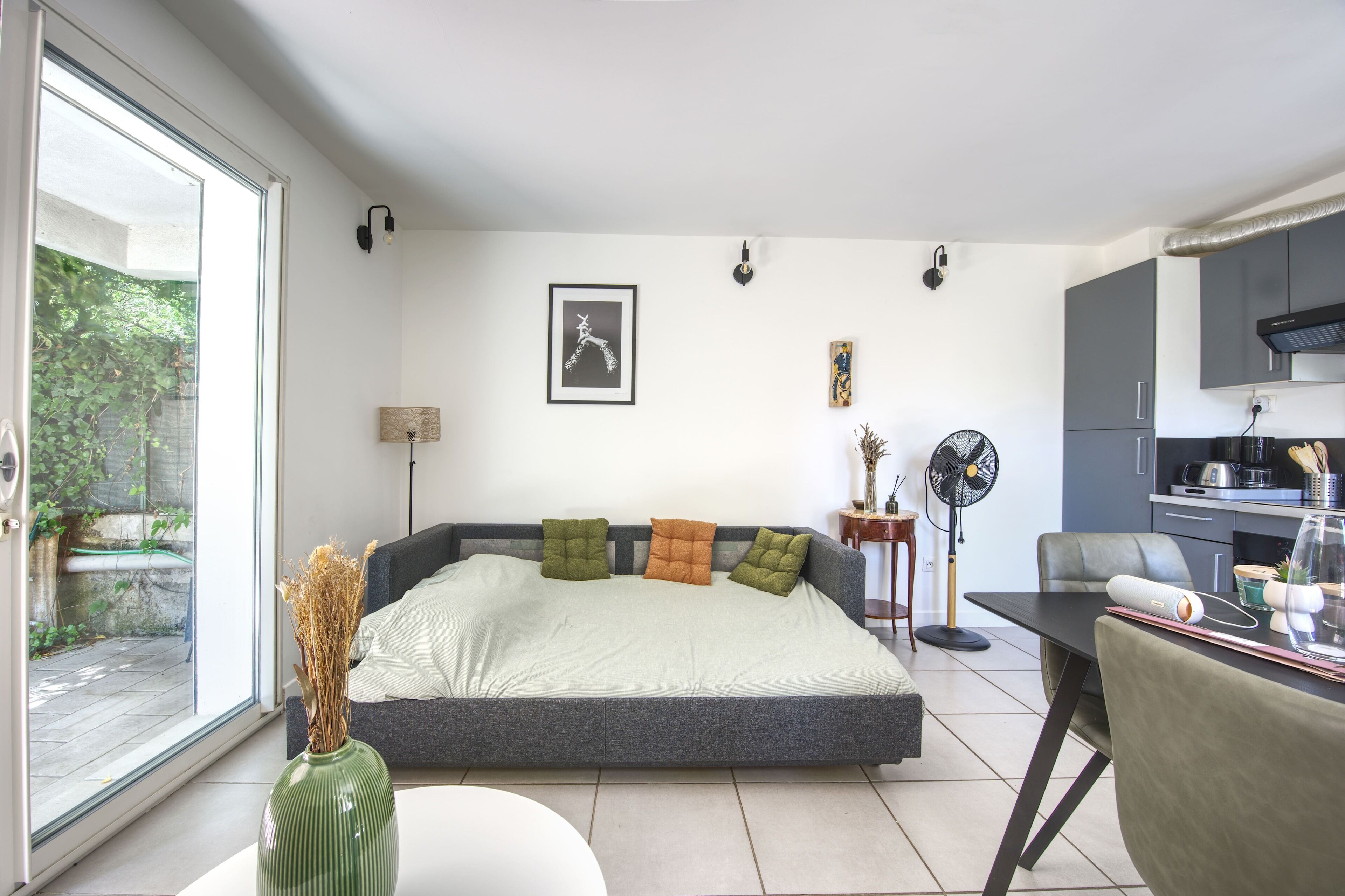 A modern bedroom with a large bed, a dining table, and a kitchenette.