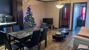 Un salon comprenant un coin repas, un téléviseur, un sapin de Noël et un canapé.