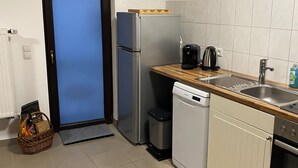 Uma cozinha compacta com geladeira, lava-louças e bancada de madeira.