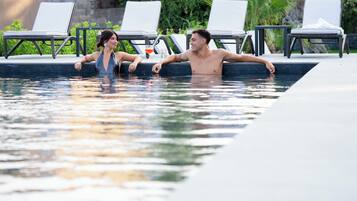 A swimming pool with lounge chairs and a table.