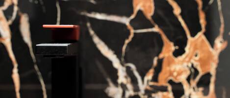 A close-up of a black object with a red top, possibly a bottle, against a background with a marbled pattern.