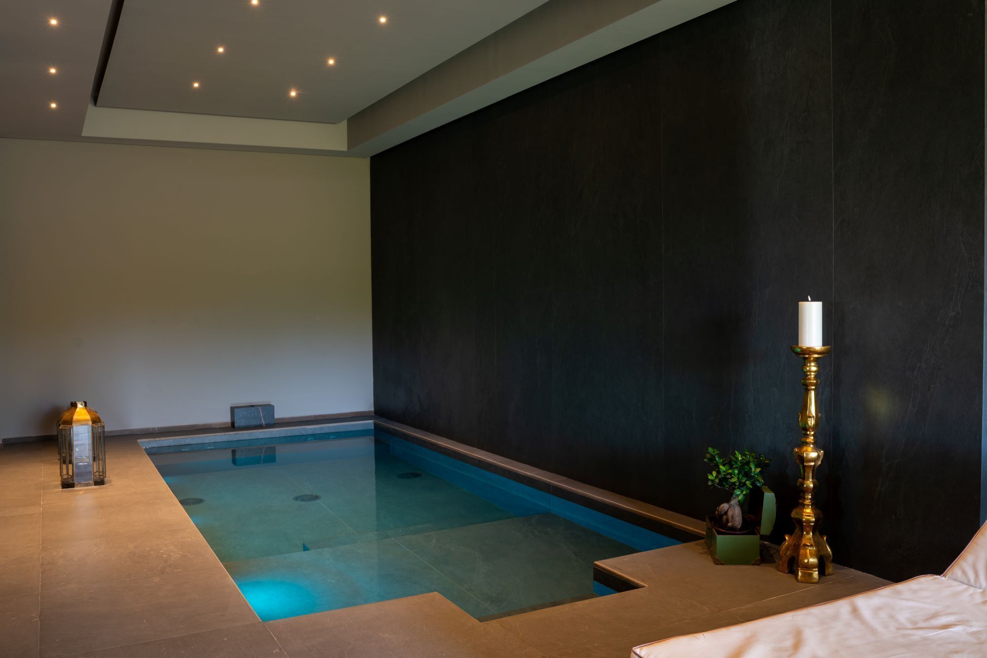 A spa room with a small pool, a candle, and a potted plant.