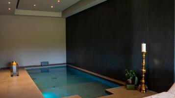 A spa room with a small pool, a candle, and a potted plant.