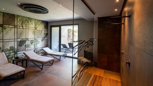 A modern spa room with a glass partition, lounge chairs, a wooden bench, and a shower area. - Mon Luxury Rooms - Spa (Nicolosi)
