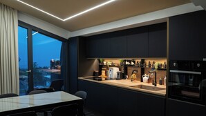 A modern kitchen with a large window, dark cabinetry, and a dining area with a table and chairs. - Mon Luxury Rooms - Spa (Nicolosi)