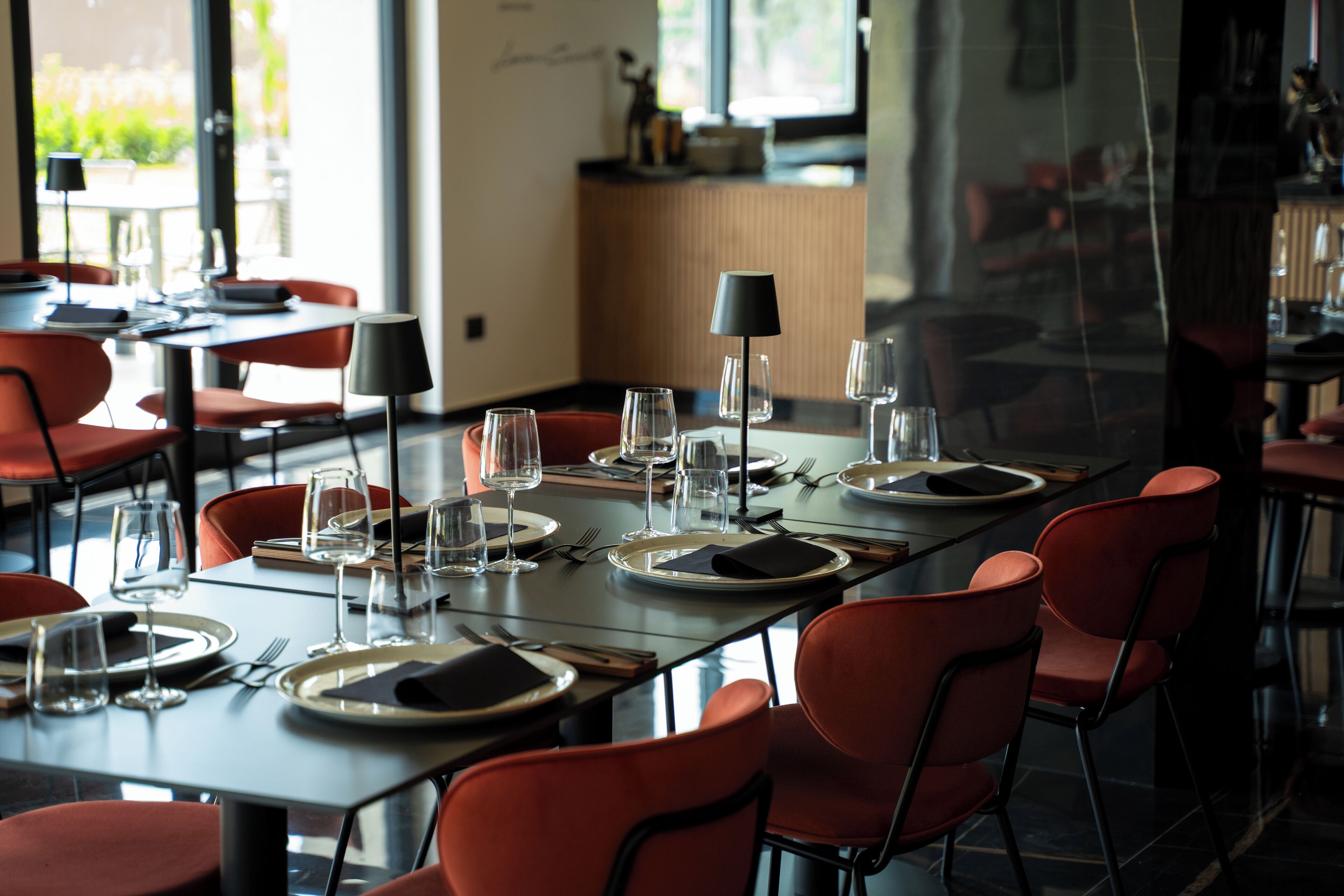 A restaurant with tables set for dining, chairs, and wine glasses.