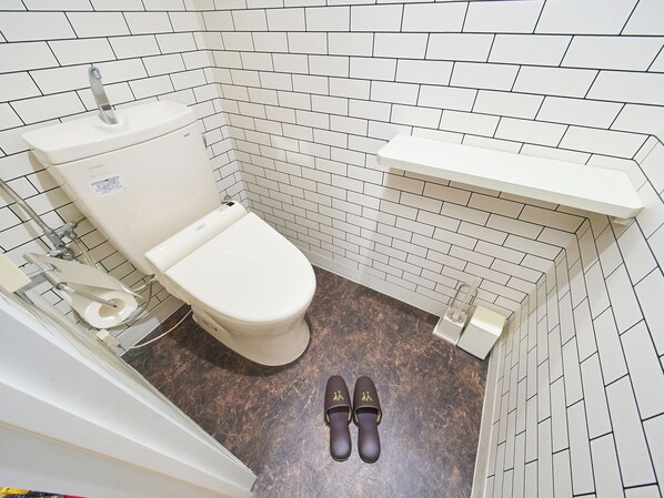 A small bathroom with a toilet, a sink, and a shower area. - HOTEL Sho (Tokyo)