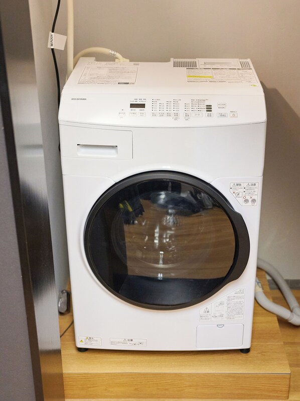 A white washing machine with a transparent door, control panel, and safety labels.