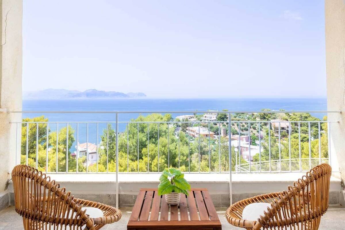 A balcony with wicker chairs, a small table, and a potted plant.