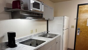 Una cocina compacta equipada con microondas, cafetera, lavabo y refrigerador.