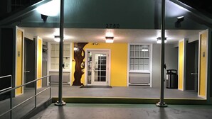 Entrada de un edificio con el número 2750, una escultura de árbol y una pared amarilla.