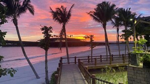 A sunset view with palm trees and a wooden walkway leading to a beach. - Labe Hotel Phu Quoc - Hon Thom Island (Phu Quoc)