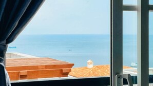 A view from a window overlooking a coastal area with a wooden deck and a small white building in the distance. - Labe Hotel Phu Quoc - Hon Thom Island (Phu Quoc)